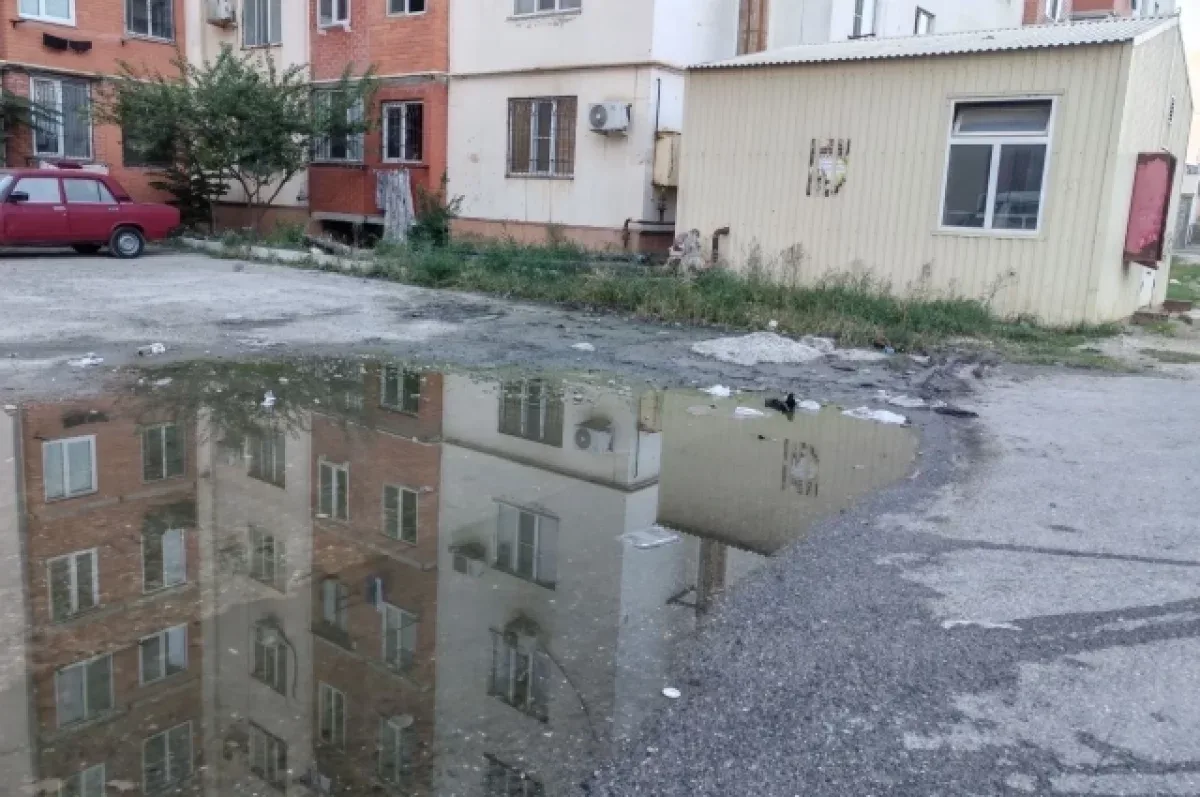 Школьники в Каспийске преодолевают лужу во дворе школы №13 для прохода к мусорным бакам