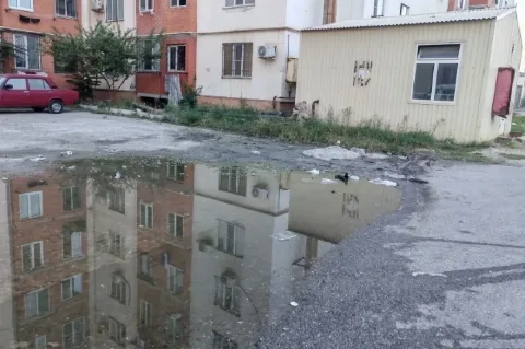 Школьники в Каспийске преодолевают лужу во дворе школы №13 для прохода к мусорным бакам